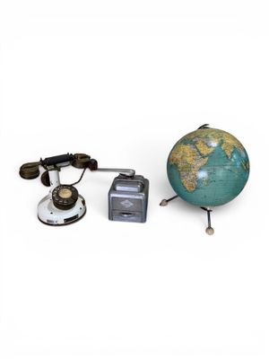 un petit globe terrestre posé à côté d'un appareil photo et d'autres objets