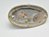 a silver and gold brooch with a picture on it