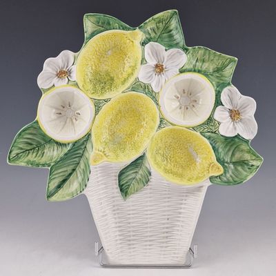 un vase en céramique contenant des citrons et des fleurs