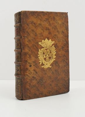 un vieux livre orné d'un emblème doré posé sur une surface blanche