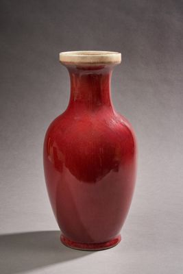 un vase rouge muni d'un couvercle en bois, posé sur une table