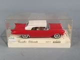 a red toy car with a white top in a clear box