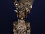 a silver statue of a woman with horns on top of a wooden base