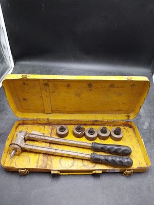 une mallette à outils jaune, contenant des outils, posée par terre