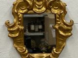 a gold mirror on a white wall with a gold frame