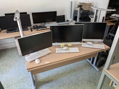 three computer monitors sitting on a desk in a room