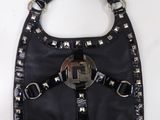 porte-monnaie en cuir noir orné de rivets et de boucles sur un fond blanc