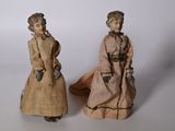 paire de poupées anciennes représentant des femmes en costume d'époque sur fond blanc