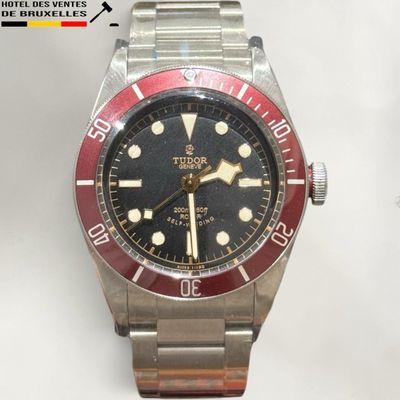 a close up of a wrist watch with a red bezel