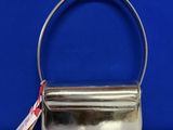 a silver purse sitting on top of a table next to a blue wall