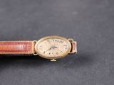 une vieille montre-bracelet avec un bracelet en cuir marron sur un fond noir