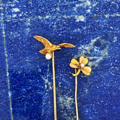 pair of gold tone bird and flower hair pins on a blue background