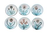 four plates with flowers and butterflies painted on them on a white surface