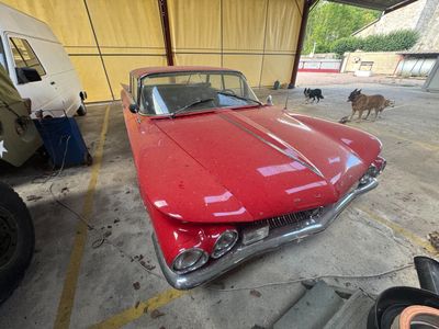 une voiture rouge garée dans un garage, à côté d'un chien