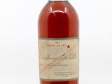 une vieille bouteille de vin posée sur une surface blanche