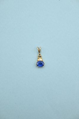 a close up of a small blue stone pendant on a white surface
