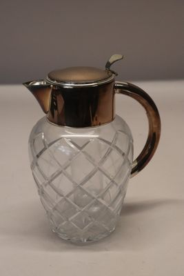 a glass pitcher with a metal lid on a table