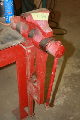 a red vise on a workbench in a garage