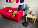 a red couch with pillows and a fan in a room