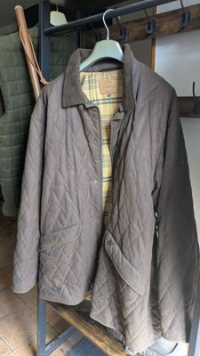 une veste matelassée marron suspendue à un porte-manteau devant une chaise