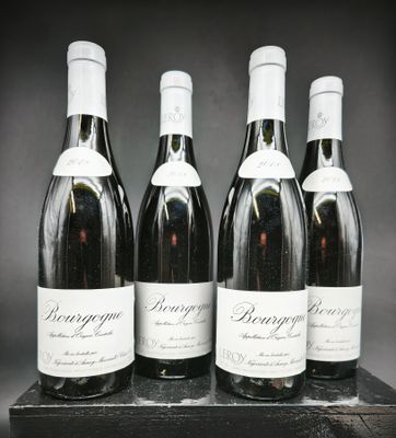 quatre bouteilles de vin sont alignées sur un support en bois