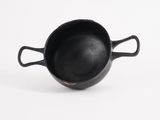 a small black pot with handles on a white surface
