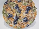 a plate with grapes and leaves on it on a white surface