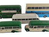 quatre petits bus jouets posés les uns à côté des autres sur une surface blanche
