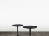 deux tables noires posées sur un sol en béton