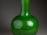 a green vase sitting on a table with a gray background