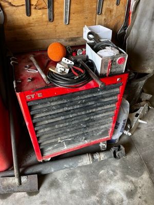 une machine rouge et noire et quelques outils dans un garage