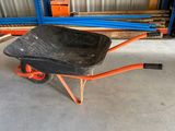 a black wheelbarrow with orange wheels in a warehouse