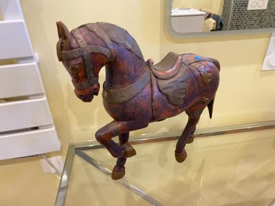 a wooden horse that is sitting on a glass table