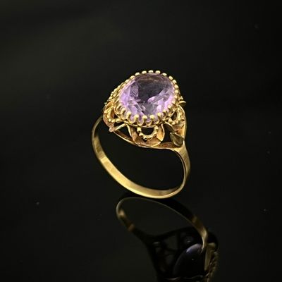 une bague en or sertie d'une pierre ovale d'améthorate entourée de filigranes