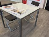 a white table with a magazine on it and a black chair in front of it