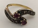 a close up of a gold and silver ring with two red stones