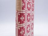 un vieux livre rouge et blanc posé sur une surface blanche