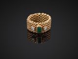 a gold ring with emerald and diamonds on a black surface