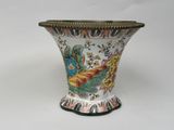 a vase that has a bird on it on a white surface