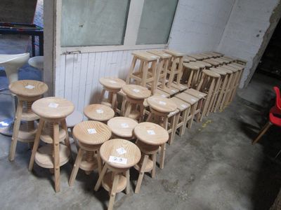 de nombreux tabourets et tables en bois dans une pièce