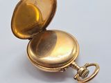 a gold pocket watch sitting on a white surface