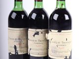trois bouteilles de vin rouge sont posées les unes à côté des autres sur une surface blanche