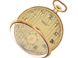 a gold pocket watch that is sitting on a white surface