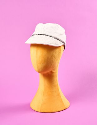 un chapeau blanc posé sur la tête d'un mannequin, sur fond rose
