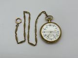 une montre de poche en or et une chaîne posées sur la table