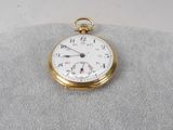 une montre de poche en or posée sur un oreiller