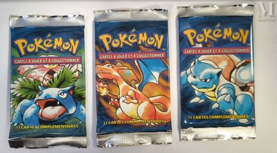 three packs of pokemon trading cards sitting on top of a counter