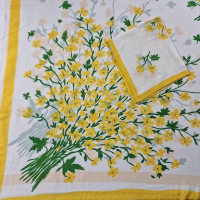 des fleurs jaunes et vertes sur une nappe blanche, avec une serviette jaune