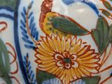 a close up of a vase with a bird and flowers on it