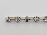 a close up of a diamond bar broocher on a white surface